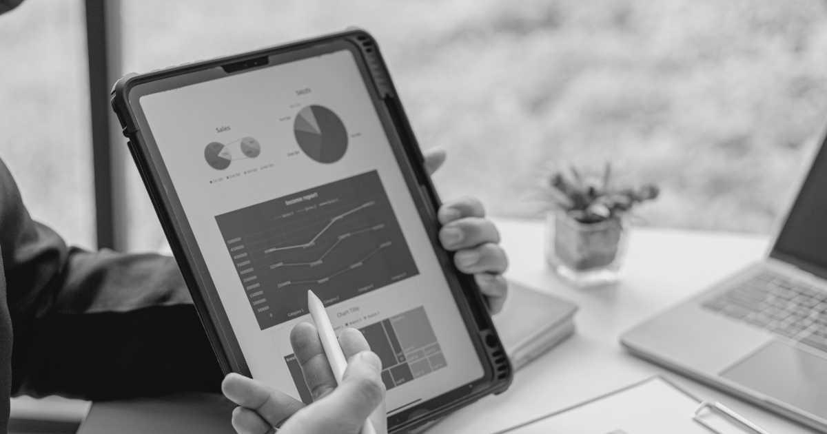 A man in a suit holds a tablet displaying performance graphs, illustrating sales tools enhanced by AI technology.