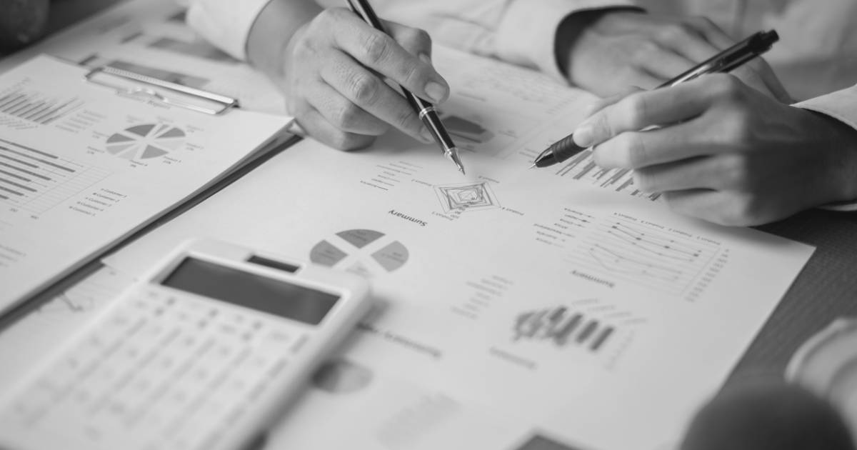 Business individuals working together on sales performance documents with a calculator and pen, focusing on analytics.