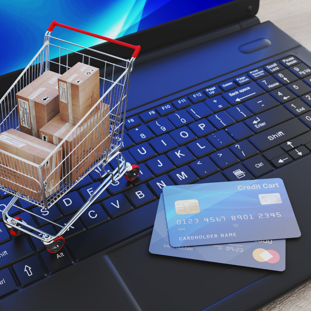 Shopping cart on a laptop keyboard with credit cards, symbolizing digital shopping and e-commerce transactions.